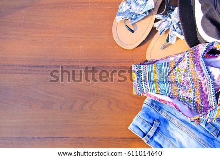 Set of beachwear on wooden background. Pink bikini, jeans shorts, sandals and hat.Summer holiday concept