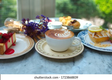 Set beautiful beverage and dessert consists hot latte coffee and strawberry cheesecake, lemon tart, scone, photogenic of food pastry lover on marble table blurred green tree in the garden background
