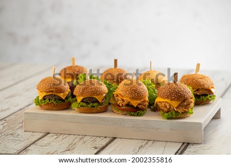 Set of Beef and Chicken mini burgers with cheese and lettuce with sticks on a wooden background 