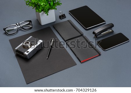 A set of black office accessories, glasses, old camera and tablet on gray background