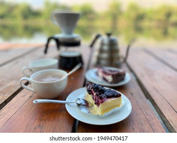 Set Of Blue Berry Cheese Cake And Slow Bar Coffee On Wood Table With Camping Background In Wild