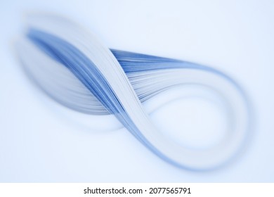 A set of blue quilling strips shot with a creative lens giving selective, shallow depth of field, shaped as an infinity sign with attractive defocussed background bokeh and space for text meta