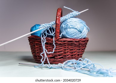 A Set Of Blue Wool Thread Balls Of Different Sizes Inside A Wicker Basket. Knitting Needles And Messy Thread. At Home Hobby. Crocheting. Balls Of Yarn.