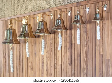 Set of brass ship's bells with ropes in boat interior