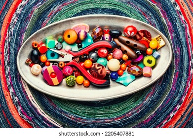 A set of bright beads of different types for needlework. Beads on a variegated background.