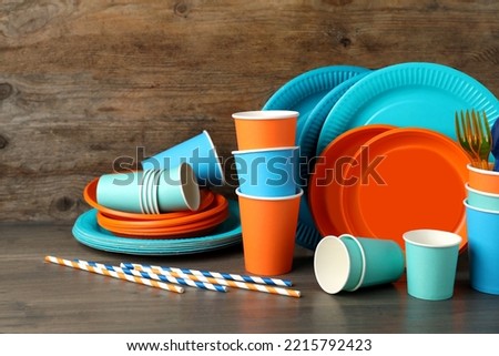 Set of bright disposable tableware on wooden table