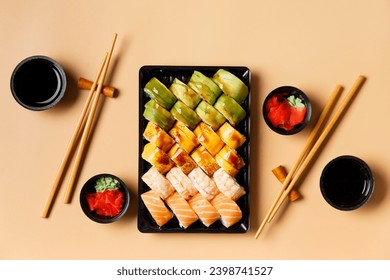 A set of bright multi-colored sushi rolls with shrimp, salmon, avocado in plastic packaging, Chinese chopsticks, sauce, ginger on a light background, top view. Sushi delivery - Powered by Shutterstock