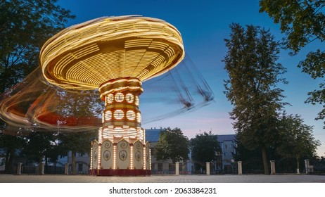 Set. Brightly Illuminated Rotating High Speed Carousel Merry-Go-Round. Summer Evening Night In City Amusement Park. Attraction Ferris Wheel On Summer Evening In City Amusement Park..