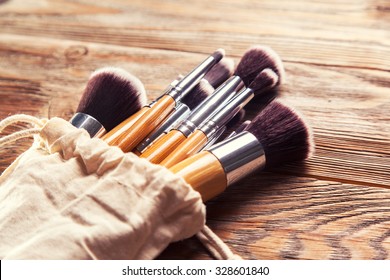 set of brushes for makeup scattered chaotically on wooden background