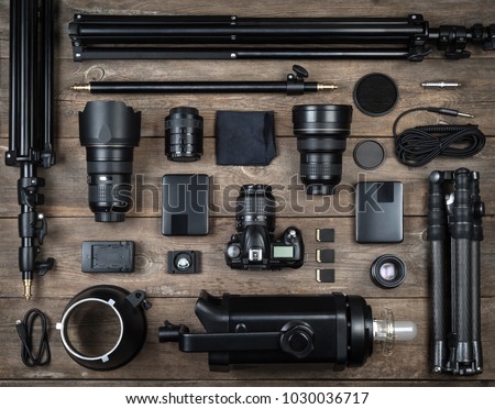 Set of the camera and photography equipment (lens, tripod, filter, flash, memory card, hard desk, reflector) on wood desk. Professional photographer accessories background.