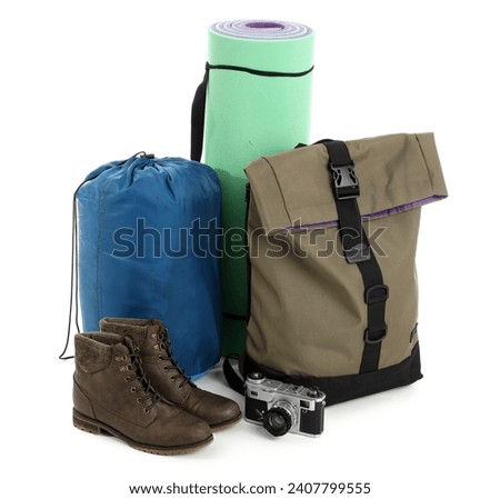 Set of camping equipment with backpack, sleeping bag and photo camera on white background