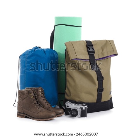 Set of camping equipment with backpack, sleeping bag and photo camera on white background