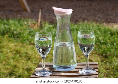 set with carafe and glasses of water outside on a wooden chair