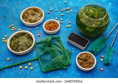 Set For The Care Of Aquarium Fish. Assorted Feed, Green Seaweed, Butterfly Net, Scraper, Brushes. Navy Blue Sea Background