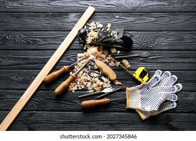 Set Of Carpenter's Tools And Saw Dust On Dark Wooden Background