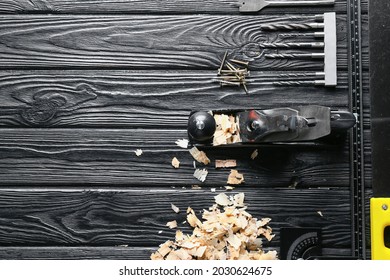 Set Of Carpenter's Tools And Saw Dust On Dark Wooden Background