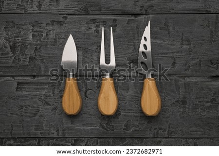 A set of cheese knives on a wooden background. Kitchen accessories. Flat lay.