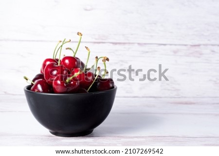 Set of cherries in black bowl and copy space