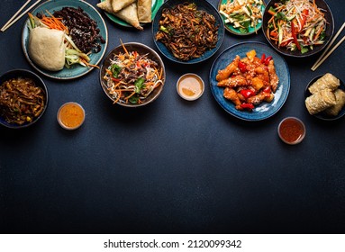 Set of Chinese dishes on table: sweet and sour chicken, fried spring rolls, noodles, rice, steamed buns with bbq glazed pork, Asian style banquet or buffet, top view with copy space - Shutterstock ID 2120099342