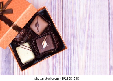 Set of chocolates stacked in a gift box standing on a wooden surface