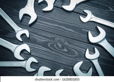 Set Of Chromed Wrenches On A Dark Wooden Workbench. Top View, Copy Space