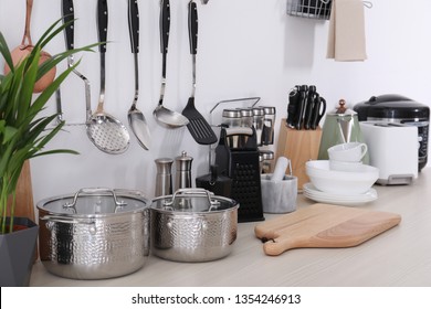 Set of clean cookware, dishes, utensils and appliances on table at white wall - Shutterstock ID 1354246913