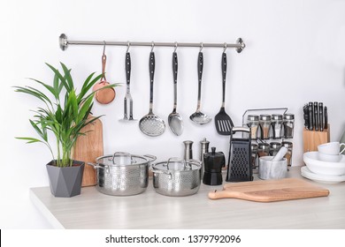 Set of clean cookware, dishes, utensils and appliance on table at white wall - Shutterstock ID 1379792096