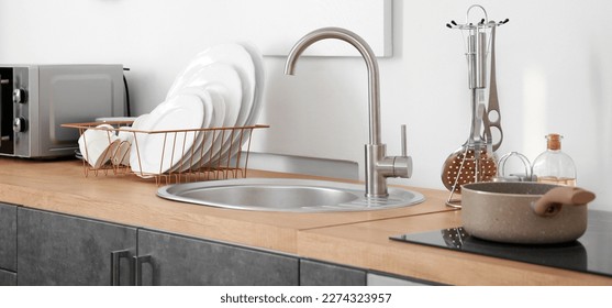 Set of clean dishes near kitchen sink on counter