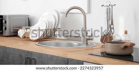 Set of clean dishes near kitchen sink on counter