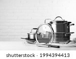Set of clean kitchenware on white table against brick wall. Space for text