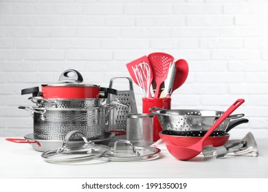 Set of clean kitchenware on white table against brick wall
