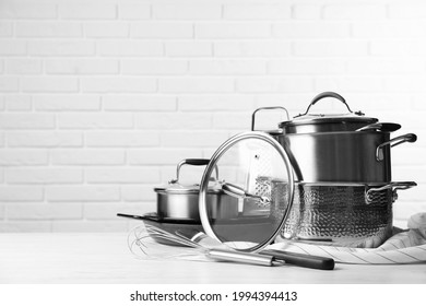 Set of clean kitchenware on white table against brick wall. Space for text