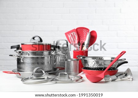 Set of clean kitchenware on white table against brick wall