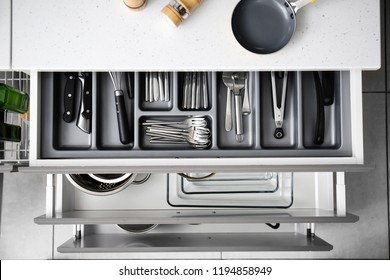Set of clean kitchenware and utensils in drawers