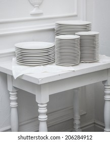Set of clean plates at the white table  in the restaurant.