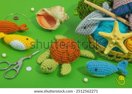 Set of clew of thread for knitting. Crocheted different underwater animals, handmade marine hobby concept. Props and special craft tools on green background, close up
