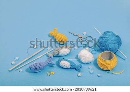 Set of clew of thread for knitting. Crocheted different fishes, handmade, sea hobby concept. Props and special craft tools on blue background, copy space