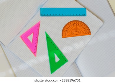 Set of colored instruments for geometry on background of open notebooks, top view