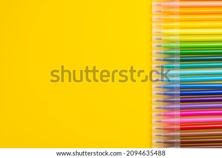 A set of colored markers.  Office and school supplies. Flat lay composition with markers and space for text on color background. Colored markers isolated on yellow background.