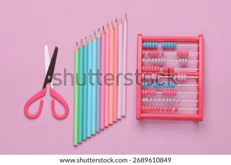 Set of colored pencils and scissors for creativity, abacus on pink background. School stationery supplies. Flat lay