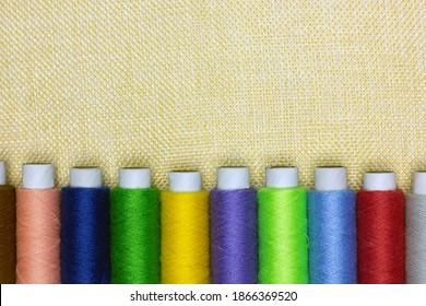 Set of colored sewing threads spools on the fabric. Needlework concept. Copy space, flat lay.
