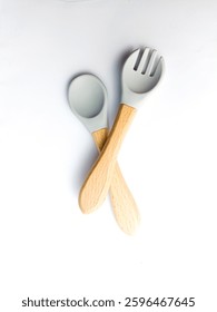 Un juego de tenedores de silicona de colores y cucharas con un mango de madera. Concepto de alimentación y nutrición del bebé. Vista superior, plana. silicona plástica. cuchara gris tenedor y cuenco. regalo gris para un bebé recién nacido 