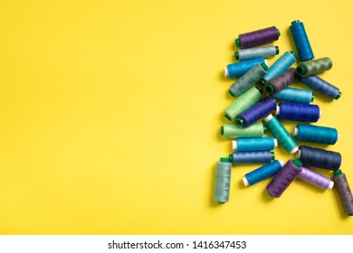 Set of colored thread coils on yellow background, sewing and tailoring. Textile background. Space for text in the left. Banner, book or magazine cover,Top view, flat lay