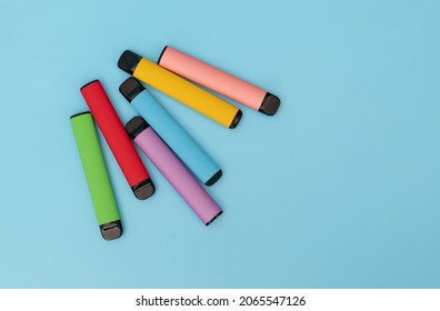 Set of colorful disposable electronic cigarettes on a blue background. The concept of modern smoking. Top view
