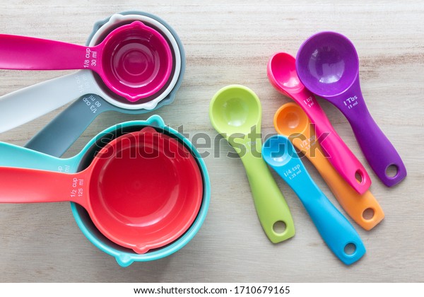 Set of colorful measuring\
cups and measuring spoons use in cooking lay on wood tabletop in\
top view.