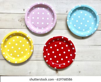A set of colorful polka dots paper plates on wooden background. Colorful paper plates for party. The concept of party accessories. Focus some points.