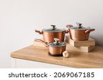 Set of copper cooking pots with garlic on counter near light wall