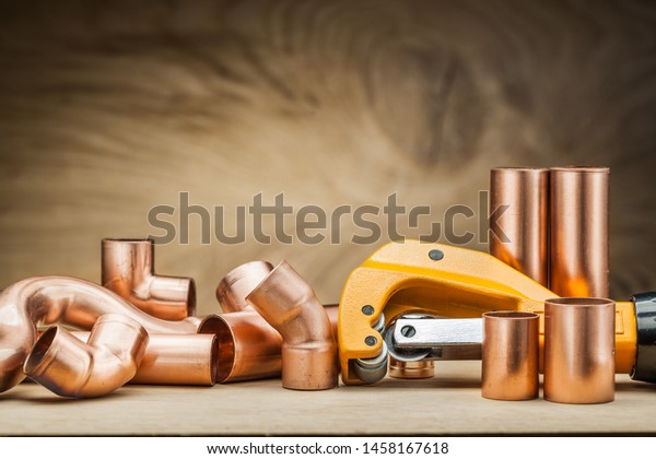 set of copper pipe fittings and  pipe cutter\
on vintage wood background