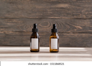 Set of cosmetic dark amber glass bottles with white labelson wooden background. Closeup, copyspace. Beauty blogging, salon treatment concept, minimalism brand packaging mock up
