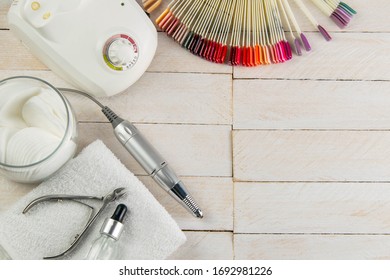 A set of cosmetic tools for manicure and pedicure on a blue background. Fraser, cotton pads, on a white towel there is oil for hands and cuticles, next to there is a palette of colors of gellaks on